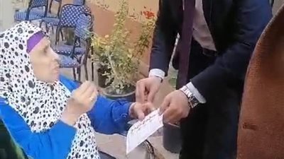 قاض يساعد ناخبة مُسنة للإدلاء بصوتها في المحلة الكبرى